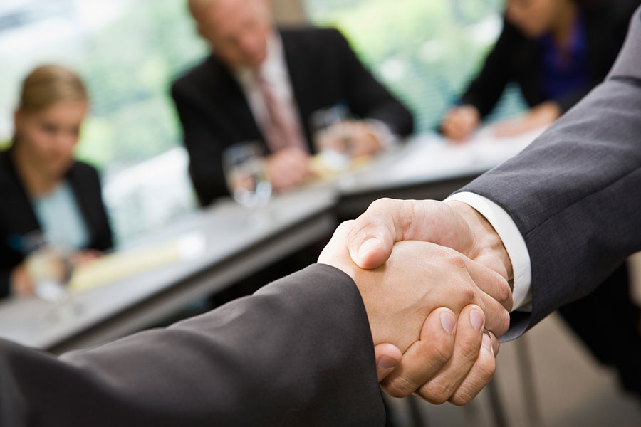 Close up of businessmen shaking hands in conference room